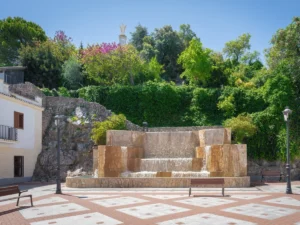 Fountain at Plaza de Andalucia Square and Penon del Sagrado Corazon Monument in Olvera